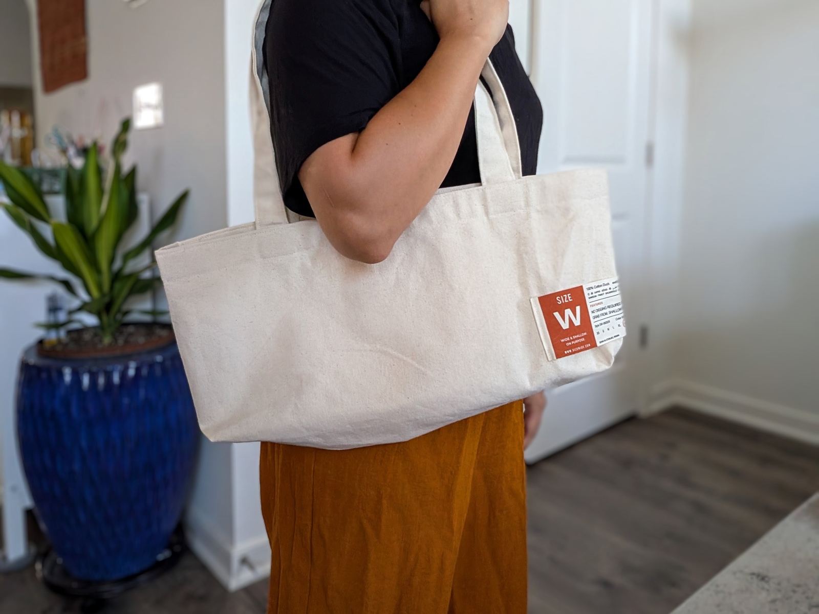 The tote carried at the hip, showing how wide it sits against the body.