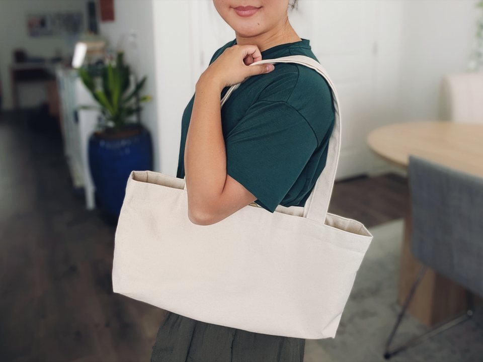 The SIZE WIDE canvas tote, wide and shallow, bag on shoulder
